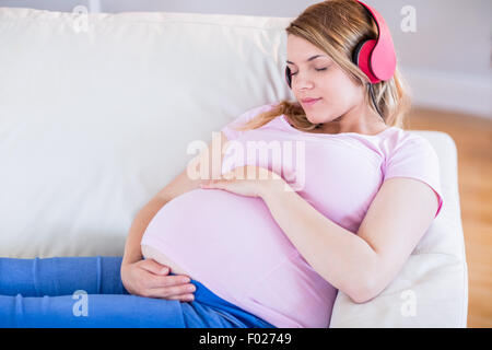 Femme enceinte l'écoute de la musique et de toucher son ventre Banque D'Images