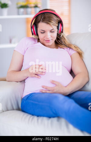 Femme enceinte l'écoute de la musique et de toucher son ventre Banque D'Images