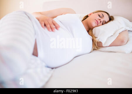 Pregnant woman sleeping on bed Banque D'Images
