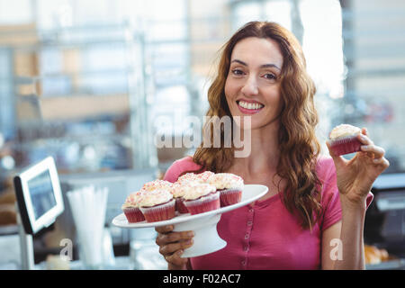 Belle brune montrant cupcake Banque D'Images