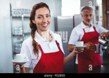 Jolie tenue barista tasses de café avec collègue derrière Banque D'Images