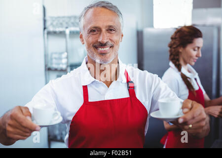 Smiling barista holding tasses de café avec collègue derrière Banque D'Images