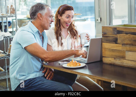 Heureux couple regardant quelque chose d'amusant sur l'ordinateur portable Banque D'Images