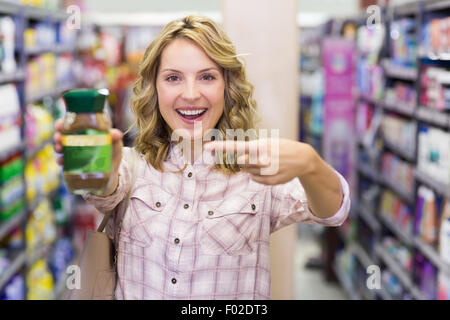 Happy smiling blonde woman montrant un produit Banque D'Images