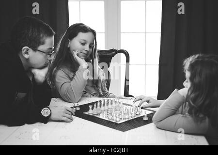 Trois enfants jouant un jeu d'échecs Banque D'Images