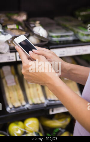 Femme lisant sa liste de courses sur smartphone Banque D'Images