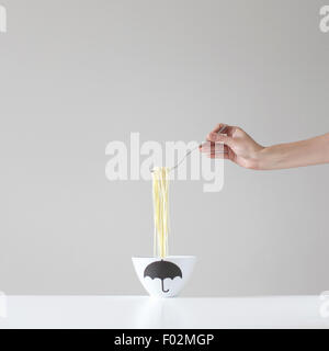 Main tenant une forkful au-dessus d'un bol de spaghetti Banque D'Images