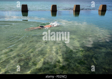 Homme natation en piscine à côté de la mer, Ross Jones Memorial Pool, Coogee Beach, Sydney, Australie Banque D'Images