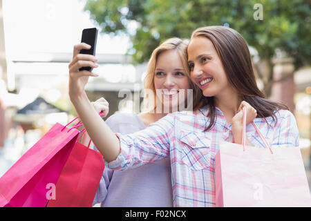 Les femmes prenant un heureux amis selfies et holding shopping bags Banque D'Images