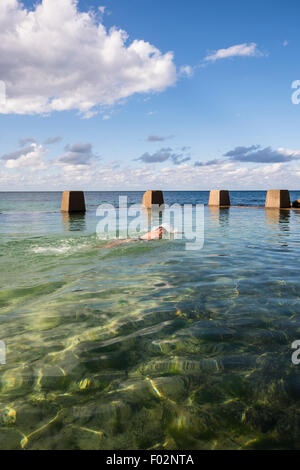 Homme natation en piscine à côté de la mer, Ross Jones Memorial Pool, Coogee Beach, Sydney, Australie Banque D'Images