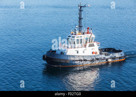 Petit bateau remorqueur avec superstructure blanc et bleu foncé coque en cours sur l'eau de mer Banque D'Images