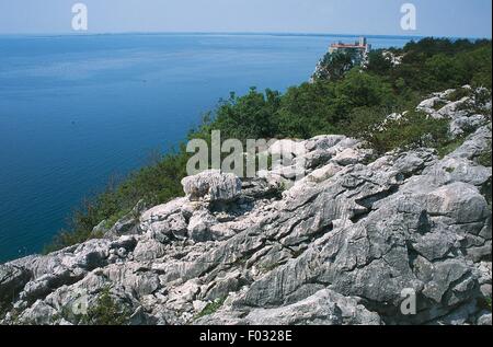 Formations karstiques le long de la côte du golfe de Trieste, Château de Duino dans l'arrière-plan, Frioul-Vénétie Julienne, Italie. Banque D'Images