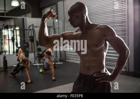 Bodybuilder jeunes posant avec ses collègues dans l'arrière-plan Banque D'Images