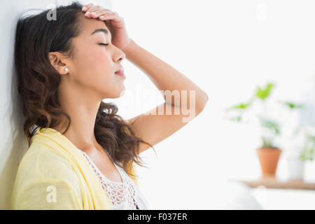 Les jeunes pensant businesswoman leaning against a wall Banque D'Images