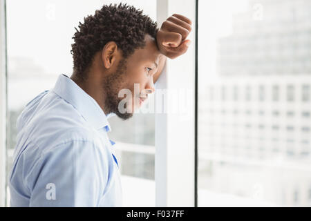 Jeune homme concentré en regardant par la fenêtre Banque D'Images