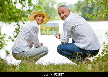 Des cadres supérieurs de la peinture dans la classe d'art dans la nature sur un lac Banque D'Images