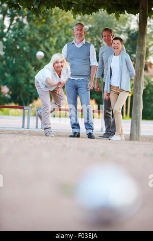 Woman throwing ball tout en jouant le jeu de la boule avec des cadres supérieurs Banque D'Images