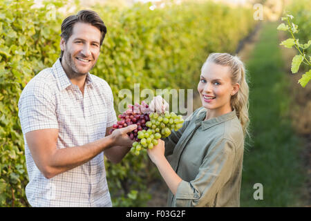 Deux jeunes vignerons heureux holding grapes Banque D'Images