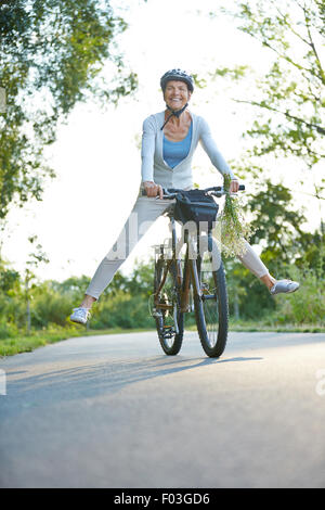 Happy senior woman having fun riding son vélo en été Banque D'Images