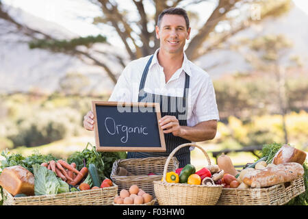 Smiling farmer holding un signe biologique Banque D'Images