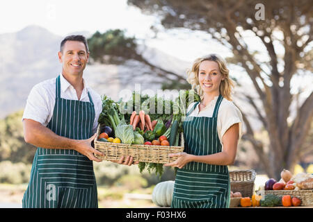 Smiling farmer couple tenant un panier de légumes Banque D'Images