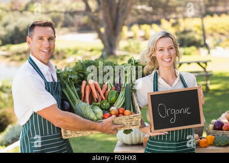 Smiling farmer couple tenant un panier de légumes Banque D'Images