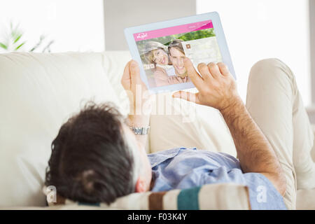 Image composite de l'homme portant sur canapé à l'aide d'un tablet pc Banque D'Images