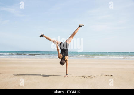 Fit woman cartwheeling sur le sable Banque D'Images