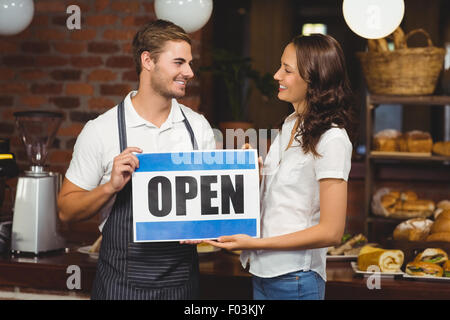 L'équipe souriante posant avec open sign Banque D'Images