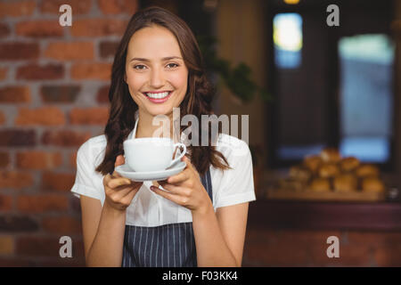 Jolie serveuse offrant une tasse de café Banque D'Images