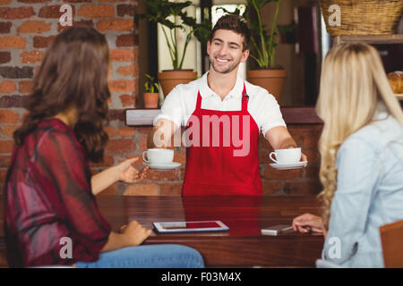 Smiling waiter sert du café aux clients Banque D'Images