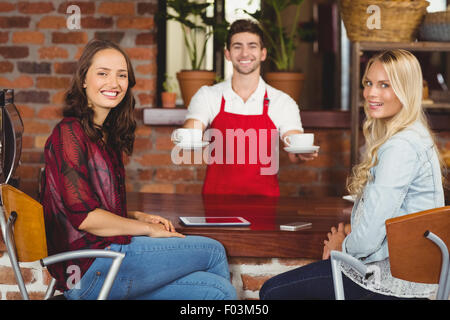 Smiling waiter sert du café aux clients Banque D'Images