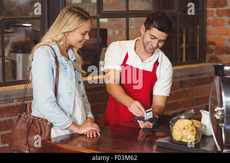 Smiling waiter glisser la carte de crédit Banque D'Images