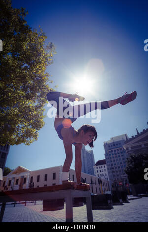 Athletic woman performing handstand on bench Banque D'Images