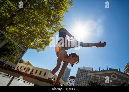 Athletic woman performing handstand on bench Banque D'Images