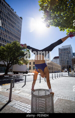 Athletic woman performing handstand et faire diviser au bin Banque D'Images