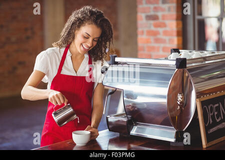 Smiling barista de verser le lait dans une tasse Banque D'Images