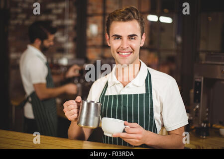 Smiling barista de verser le lait dans une tasse Banque D'Images