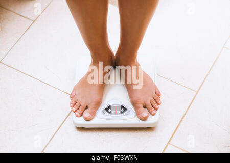 Femme pesant elle-même pieds nus sur un pèse-personne Banque D'Images