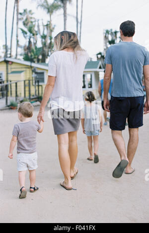 Vue arrière d'une famille, un couple en train de marcher avec leur jeune fils et fille. Banque D'Images