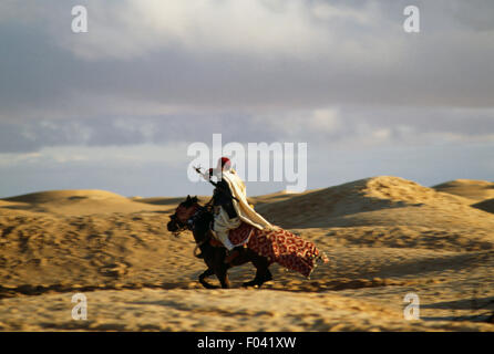 Cavalier berbère en vêtements traditionnels tenant un fusil, Festival du Sahara à Douz, Tunisie. Banque D'Images