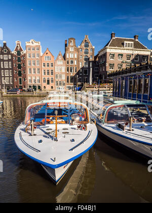 Bateau de tourisme de croisière sur un canal Damrak à Amsterdam, Pays-Bas, un jour d'été. Maisons traditionnelles dans l'arrière-plan. Banque D'Images