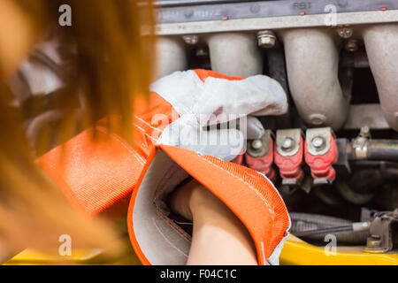 Mécanicien automobile dans son atelier de réparation debout à côté de la voiture - close-up du moteur Banque D'Images