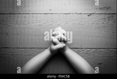 Les mains de l'enfant pliées ensemble dans la prière. Photo en noir et blanc Banque D'Images