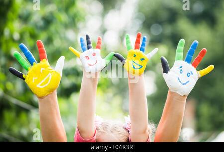 Les mains de couleur avec sourire peint dans les peintures colorées contre green summer background. Concept de vie Banque D'Images