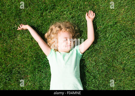 Adorable rêve girl lying on grass, vue du dessus Banque D'Images