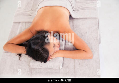 Jeune femme dormir sur une chaise longue massage dans un centre de bien-être isolé sur fond blanc Banque D'Images