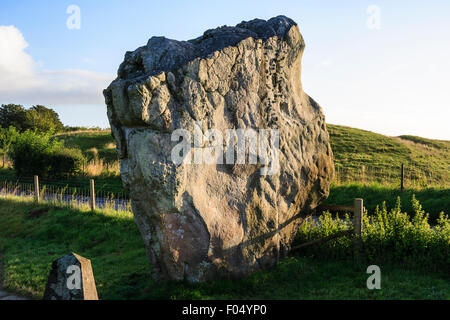 Avebury Stone Circle, néolithique henge. L'énorme mégalithe Swindon pierre debout à côté d'une route dans la lumière du matin. Ciel bleu. Banque D'Images