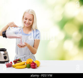 Femme souriante avec le mélangeur et milk-shake aux fruits Banque D'Images