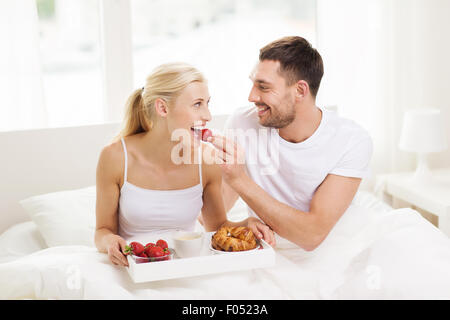 Heureux couple having breakfast in bed at home Banque D'Images